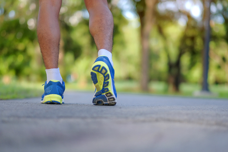 young fitness man legs running in the park outdoor, male runner walking on the road outside, asian athlete jogging and exercise on footpath in sunlight morning. Sport, healthy and wellness conceptsの写真素材