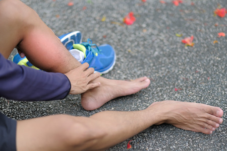 Young fitness man holding his sports leg injury, muscle painful during training. Asian runner having...