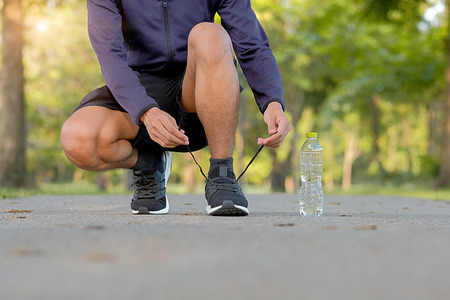 young fitness man legs walking in the park outdoor, male runner running on the road outside, asian athlete jogging and exercise on footpath in sunlight morning. Sport,healthy and wellness conceptsの写真素材