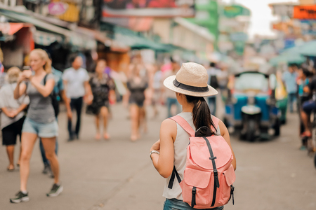 Young Woman traveling with hat, Asian hipster traveler walking at famous backpacker street in Bangkok (Khao San road), landmark and popular for tourist attractions in Thailand. Travel conceptの写真素材