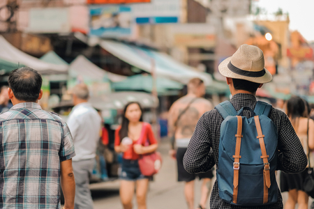 Young man traveling with hat, Asian hipster traveler walking at famous backpacker street in Bangkok (Khao San road), landmark and popular for tourist attractions in Thailand. Travel conceptの写真素材