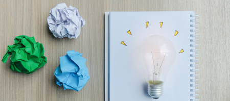 light bulb or lamp with colorful crumpled paper on wooden table. New Idea, Creative, Genius and Innovation conceptsの写真素材