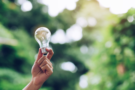 Hand holding light bulb with green background. New Idea, Creative, Genius, Innovation and solar energy conceptsの写真素材