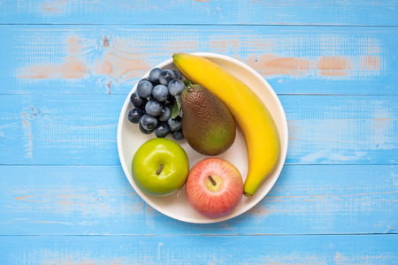 green apple, red apple, Avocado, banana and grape on blue wooden background. World Food Day Concept (October 16), Top view and Copy space for your textの写真素材