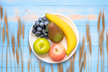Wheat ears grain, green apple, red apple, Avocado, banana and grape on blue wooden background. World Food Day Concept (October 16), Top view and Copy space for your textの写真素材
