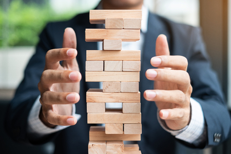 Businessman hand cover wooden block on the tower. Business planning, Risk Management, Solution and strategy Conceptsの写真素材