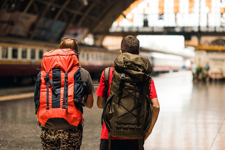 couple  traveler with backpack waiting for train, Asian backpacker with hat standing on railway platform at Bangkok train station. Holiday, journey, trip and summer Travel conceptの写真素材