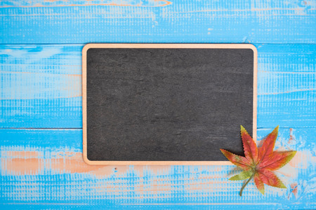 Autumn Maple leaves and chalkboard with handwritten words on blue wooden background. Top view and Copy space for your textの写真素材