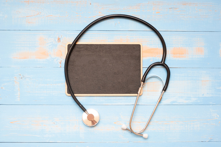 Stethoscope and chalkboard with handwritten words on blue  wooden background. Healthcare and Insurance concept, Top view and Copy space for your textの写真素材