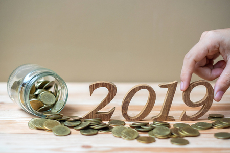 businessman putting  â2019â wooden number with gold coins stack on wooden table. business, investment, retirement planning, finance, Saving and New Year Resolution conceptsの写真素材