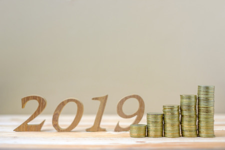 2019 Happy New Year with gold coins stack and wooden number on table. business, investment,...