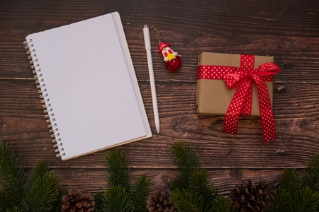 blank notebook with Christmas decoration, gift box and pine tree branches on wooden background, preparation for holiday concept, Happy New Year and Xmas Holidays. Top view and Copy Space for textの写真素材