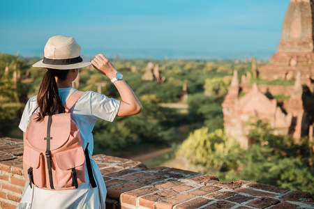 Young woman traveling backpacker with hat, Asian traveler standing on Pagoda and looking Beautiful ancient temples, landmark and popular for tourist attractions in Bagan, Myanmar. Asia Travel conceptの写真素材