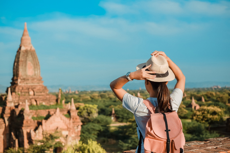 Young woman traveling backpacker with hat, Asian traveler standing on Pagoda and looking Beautiful ancient temples, landmark and popular for tourist attractions in Bagan, Myanmar. Asia Travel conceptの写真素材