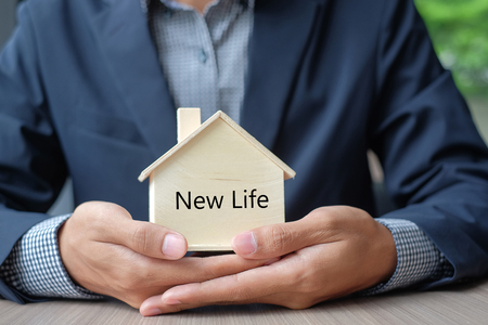 Businessman hands holding wooden House model. Property insurance and real estate conceptsの写真素材