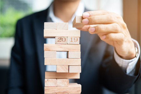 Businessman hand placing or pulling wooden block on the tower. Business planning, Risk Management, Solution and strategy Conceptsの写真素材