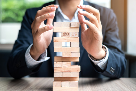 Businessman hand cover wooden block on the tower. Business planning, Risk Management, Solution and strategy Conceptsの写真素材