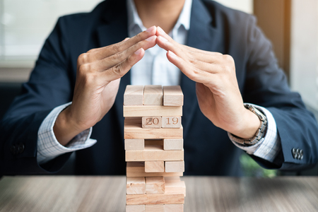 Businessman hand cover wooden block on the tower. Business planning, Risk Management, Solution and strategy Conceptsの写真素材