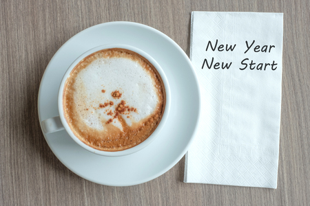 NEW YEAR NEW START word with hot cappuccino coffee cup on table background at the morning. Resolution, Solution, Strategy and Mission conceptの写真素材