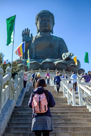 Young woman traveling backpacker, Asian traveler visit the Tian Tan or Big Buddha located at Po Lin Monastery in Ngong Ping Lantau Island. landmark and popular for tourist attractions in Hong Kongの写真素材
