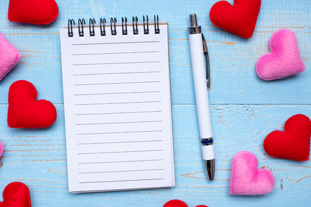 Blank note book and pen with red and pink heart shape decoration on blue wooden table background. Love, Wedding, Romantic and Happy Valentineâ s day holiday conceptの写真素材