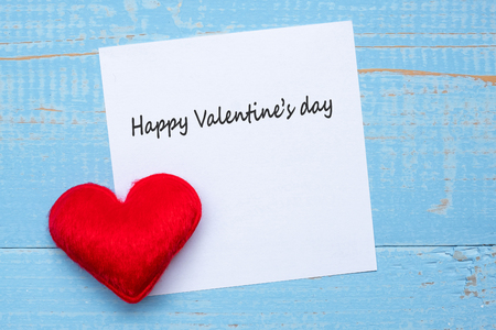 HAPPY VALENTINE'S DAY word on paper note with red heart shape decoration on blue wooden table background. Love, Wedding, Romantic and holiday conceptの写真素材