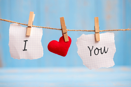 I LOVE YOU word on paper and red heart shape decoration hanging on line with copy space for text on blue wooden background. Love, Wedding, Romantic and Happy Valentineâ s day holiday conceptの写真素材