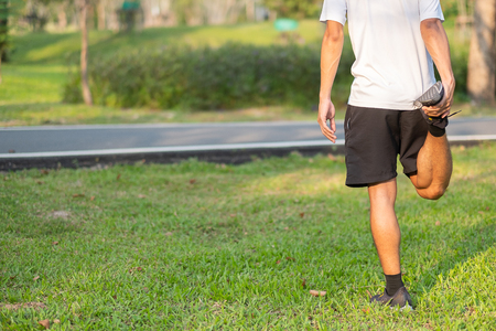 Young athlete man streching in the park outdoor. male runner warm up ready for jogging on the road outside. asian Fitness walking and exercise on footpath in morning. wellness and sport conceptsの写真素材
