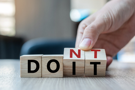 Business man hand holding wooden cube with flip over block DON T to DO IT word on table background. success, strategy, solution, business and Positive thinking concepts