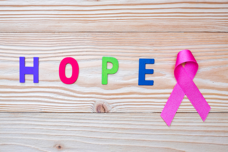 World cancer day (February 4) or Breast cancer, hope letter and pink ribbon on wooden background  for supporting people living and illness. Healthcare and medicine conceptの写真素材