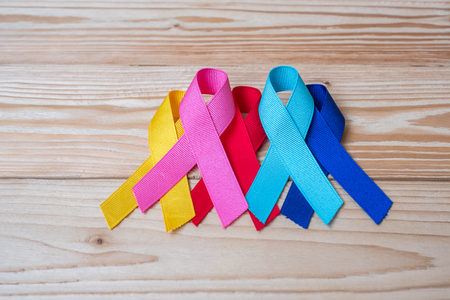 World cancer day (February 4). colorful awareness ribbons; blue, red, pink and yellow color on wooden background  for supporting people living and illness. Healthcare and medicine conceptの写真素材