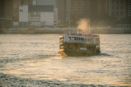 green passenger Ferry in victoria harbour with cityscape background against morining sunrise, services between Kowloon and Hong Kong Islandの写真素材