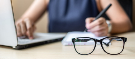 Close up eye glasses with Businesswoman using laptop analysis marketing plan background. Business, Finance and Vision conceptsの写真素材