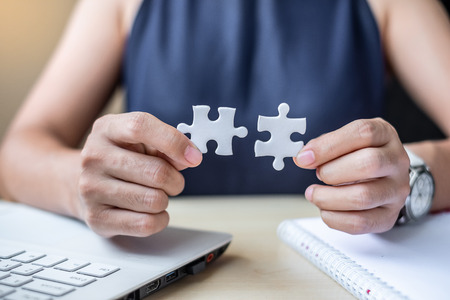 Businesswoman Hand connecting couple puzzle piece in office. Business solutions, mission,...