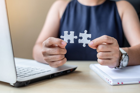 Businesswoman Hand connecting couple puzzle piece in office. Business solutions, mission, successful, goals and strategy conceptsの写真素材