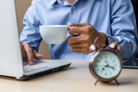 young Businessman using laptop analysis marketing plan and drinking coffee in the morning. Business, Finance and lifestyle conceptsの写真素材