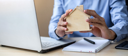 Businessman hands holding wooden House model. housing purchase, Property, real estate and insurance conceptsの写真素材