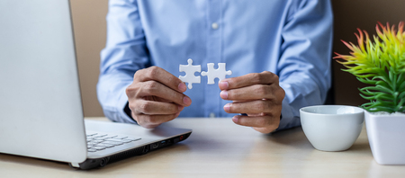 Businessman Hand connecting couple puzzle piece in office. Business solutions, mission, successful, goals and strategy conceptsの写真素材