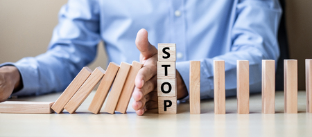 Businessman hand Stopping Falling wooden Blocks or Dominoes. Business, Risk Management, Solution, Insurance and strategy Conceptsの写真素材