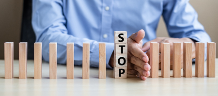 Businessman hand Stopping Falling wooden Blocks or Dominoes. Business, Risk Management, Solution, Insurance and strategy Conceptsの写真素材