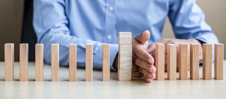 Businessman hand Stopping Falling wooden Blocks or Dominoes. Business, Risk Management, Solution, Insurance and strategy Conceptsの写真素材