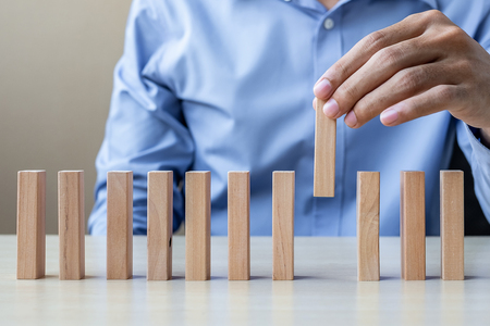 Businessman hand pulling or placing wooden Blocks or Dominoes. Business, Risk Management, Solution and strategy Conceptsの写真素材