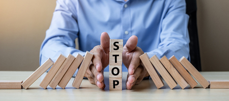 Businessman hand Stopping Falling wooden Blocks or Dominoes. Business, Risk Management, Solution, Insurance and strategy Conceptsの写真素材