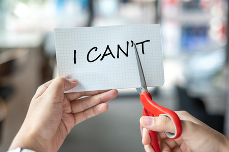 Business man hand holding red scissors and cutting white paper with the text I CAN'T change word to I CAN. challenge, positive thinking and success conceptの写真素材