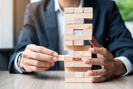 Businessman hand placing or pulling wooden block on the tower. Business planning, Risk Management, Solution and strategy Conceptsの写真素材