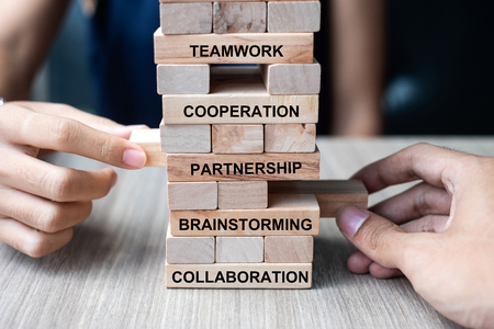 Businessman and Businesswoman hand placing or pulling wooden block on the tower building. Business, Teamwork, Brainstorming, Partnership, Collaboration and Cooperation Conceptsの写真素材