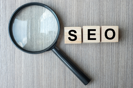 SEO (Search Engine Optimization) text wooden cubes and magnifying glass on wood table background. Idea, Vision, Strategy, Analysis, Keyword and Content conceptの写真素材