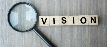 Vision text wooden cubes and magnifying glass on wood table background. SEO, Idea, Strategy, Analysis, goals and Values conceptの写真素材