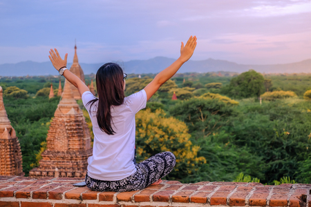 Young happy woman traveling, Asian traveler on Pagoda and looking Beautiful ancient temples, landmark and popular for tourist attractions in Bagan, Myanmar. Asia Travel conceptの写真素材