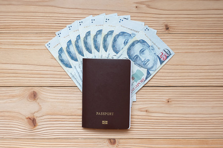 Money banknote with Passport on wooden table, Top view and copy space. Time to Travel in Singapore conceptの写真素材